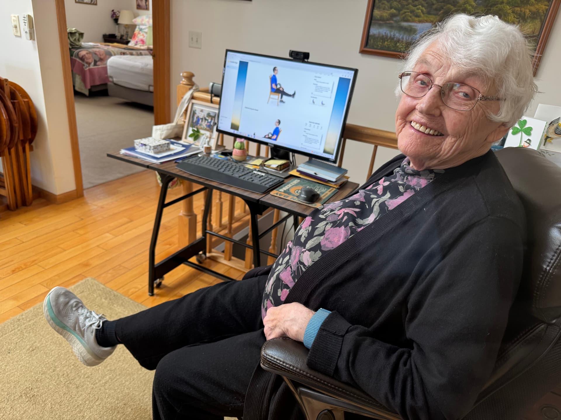 A Caring Companion client smiling while following along with a chair exercise video at home