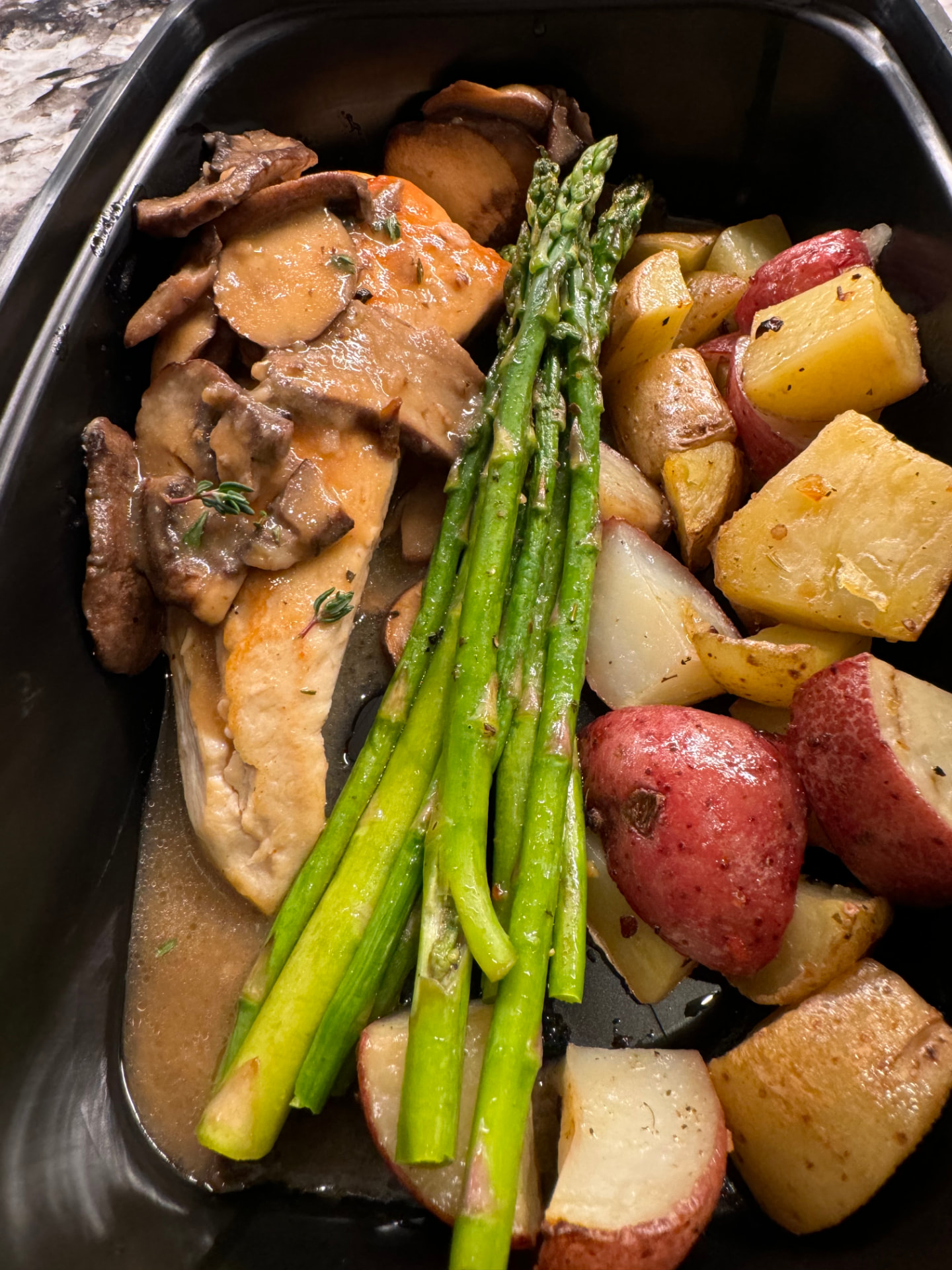 Chicken marsala with mushrooms, asparagus and roasted red potatoes in a meal container