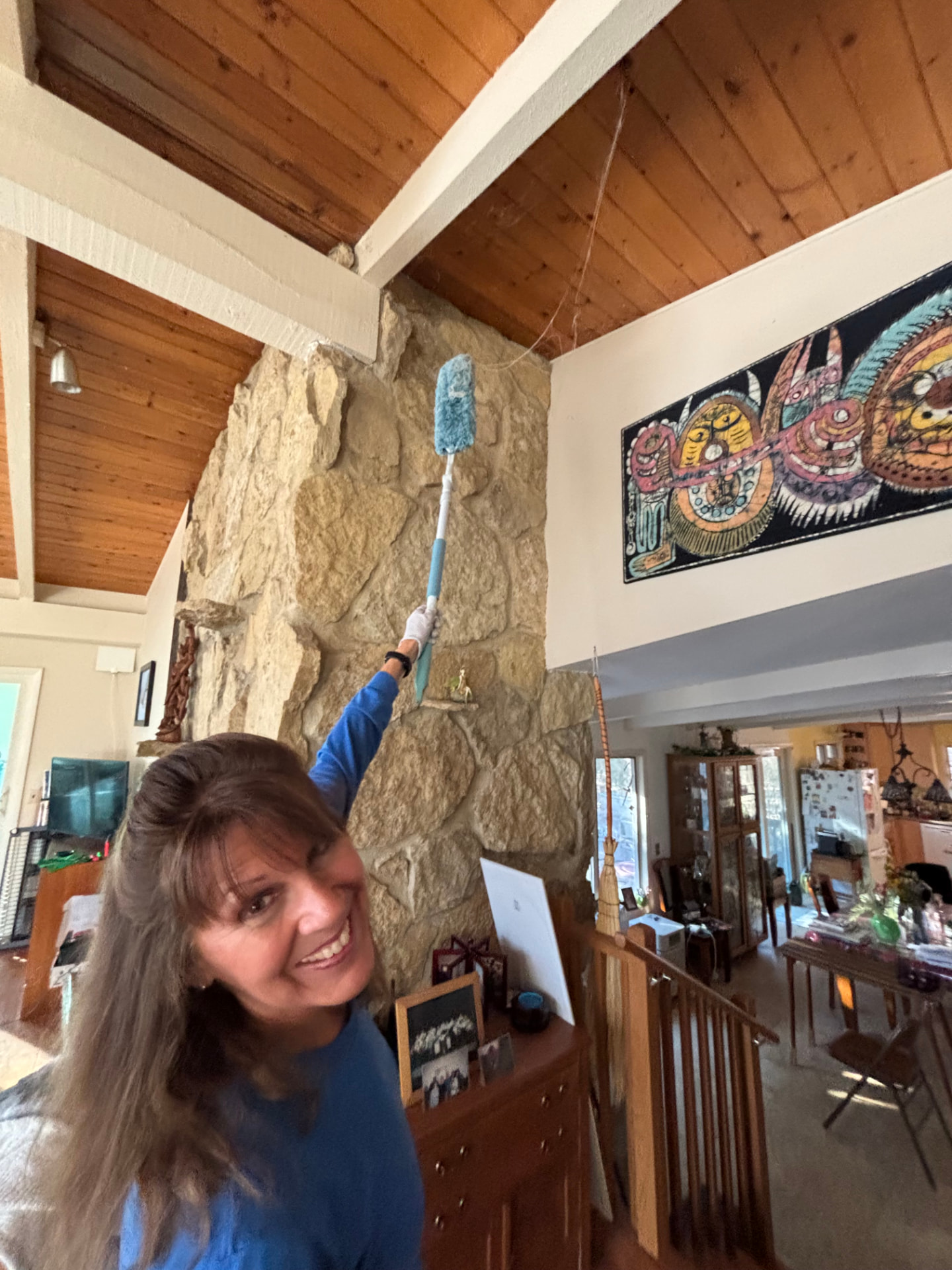 Terri dusting a stone fireplace with a long-handled duster during a light housekeeping visit